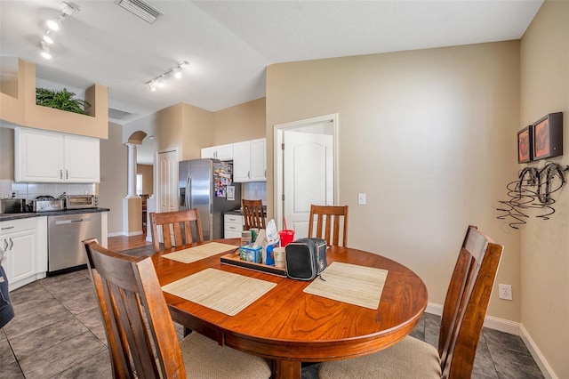 dining area featuring tile patterned flooring, vaulted ceiling, and decorative columns