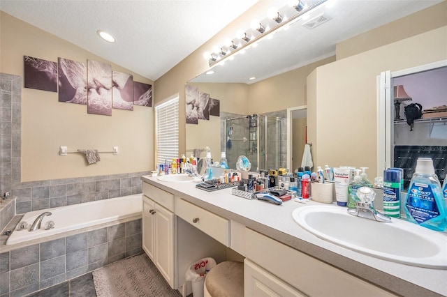 bathroom featuring vanity, independent shower and bath, and a textured ceiling