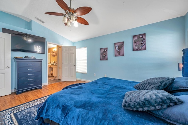 bedroom with ceiling fan, vaulted ceiling, ensuite bathroom, and hardwood / wood-style floors