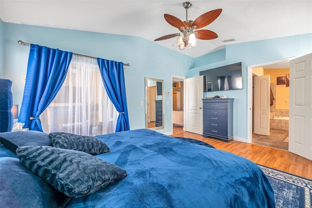 bedroom with ceiling fan, lofted ceiling, connected bathroom, and wood-type flooring