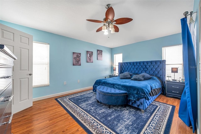 bedroom with ceiling fan, multiple windows, and wood-type flooring