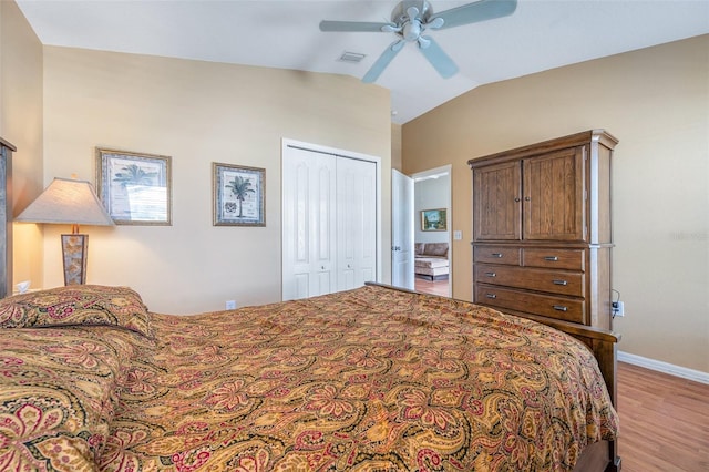 bedroom with ceiling fan, lofted ceiling, a closet, and light hardwood / wood-style flooring