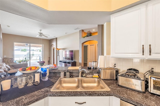 kitchen with ceiling fan, sink, white cabinetry, and backsplash