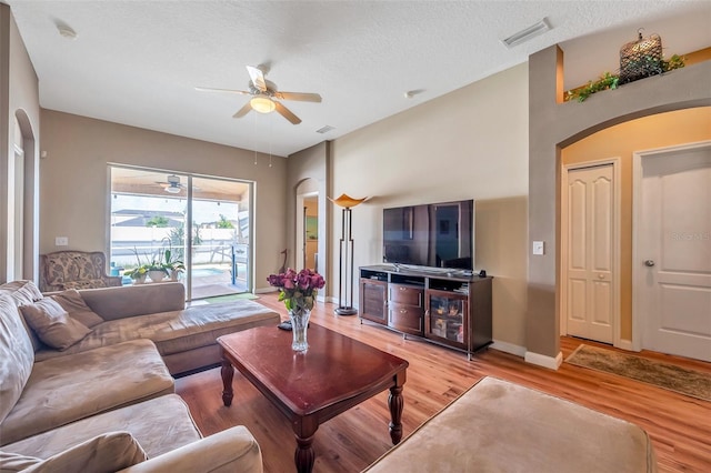 living room featuring ceiling fan, a textured ceiling, and light hardwood / wood-style flooring