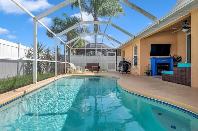 view of pool featuring glass enclosure, a patio area, and ceiling fan