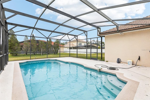 view of swimming pool featuring a yard, glass enclosure, and a patio area