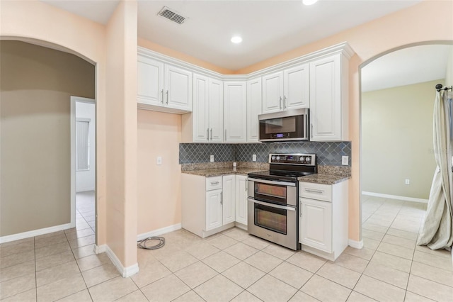 kitchen featuring white cabinetry, light stone counters, stainless steel appliances, and decorative backsplash