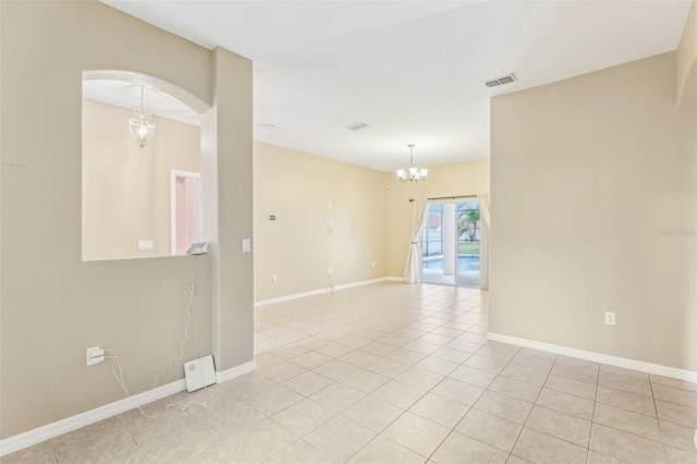 tiled spare room with a notable chandelier