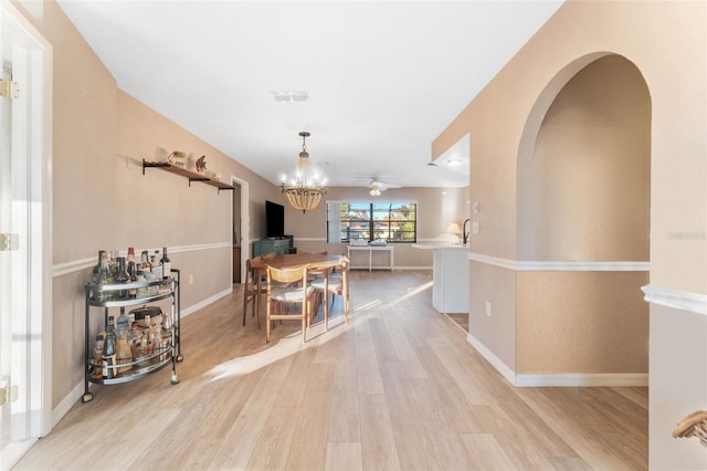 dining space featuring ceiling fan with notable chandelier and light wood-type flooring