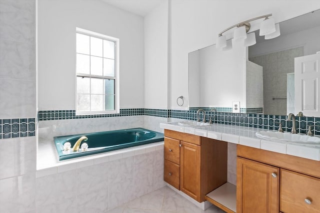 bathroom with tile patterned floors, tiled tub, and vanity