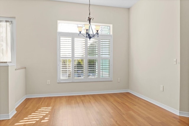 unfurnished dining area with light hardwood / wood-style flooring and an inviting chandelier