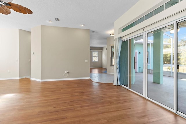 unfurnished room featuring a textured ceiling, ceiling fan, and hardwood / wood-style flooring