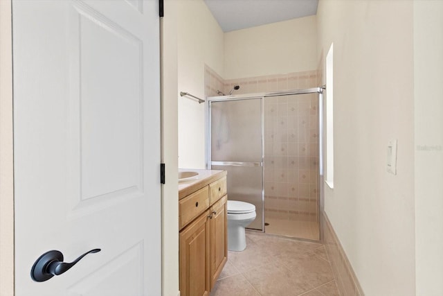 bathroom with a shower with door, vanity, tile patterned floors, and toilet