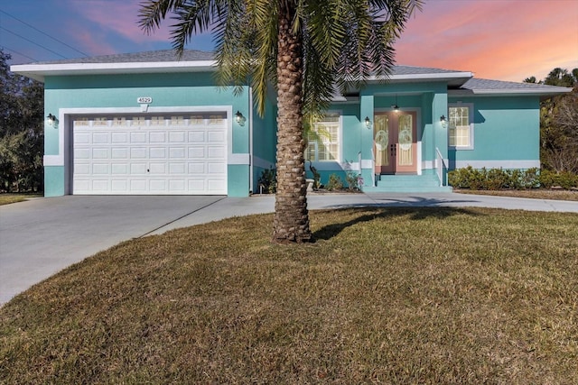 view of front of property with a garage and a yard