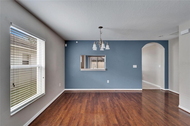 empty room featuring hardwood / wood-style flooring, a chandelier, and a textured ceiling