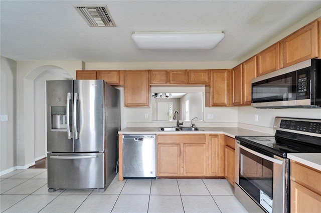 kitchen with sink, light tile patterned floors, and stainless steel appliances