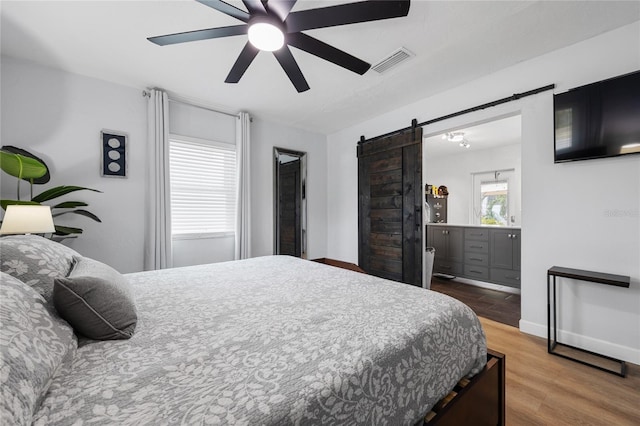 bedroom with ceiling fan, hardwood / wood-style floors, and a barn door