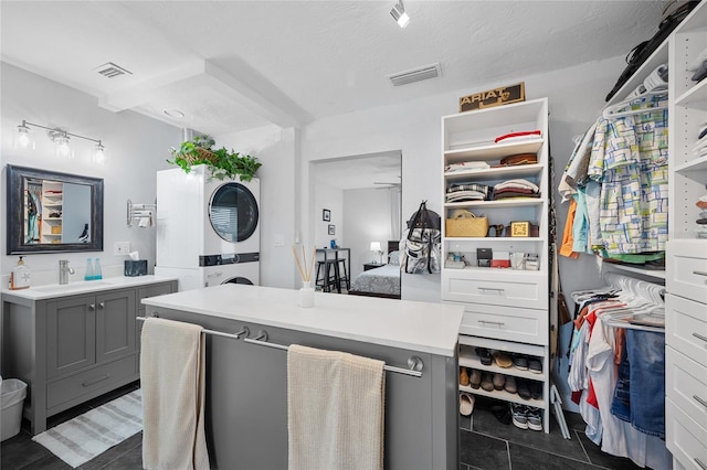 interior space featuring stacked washer and dryer, ceiling fan, tile patterned floors, a textured ceiling, and vanity