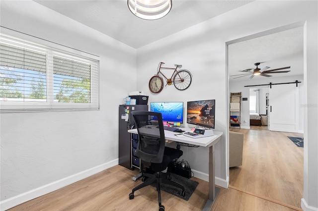 office space with ceiling fan, wood-type flooring, a textured ceiling, and a barn door