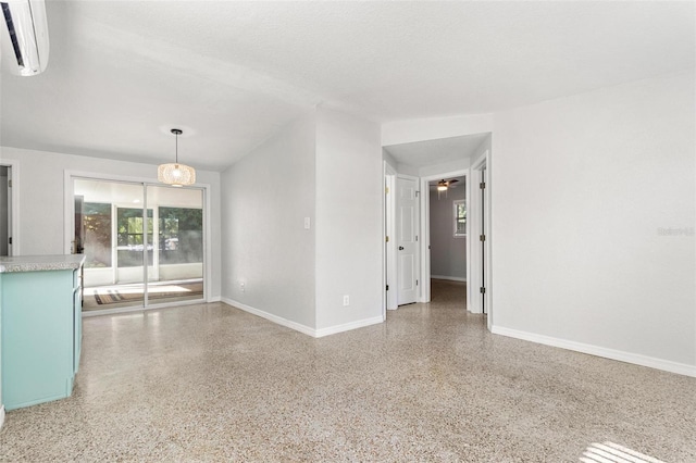 spare room featuring an AC wall unit, a textured ceiling, ceiling fan, and plenty of natural light