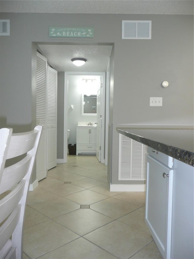 hallway featuring a textured ceiling and light tile patterned floors