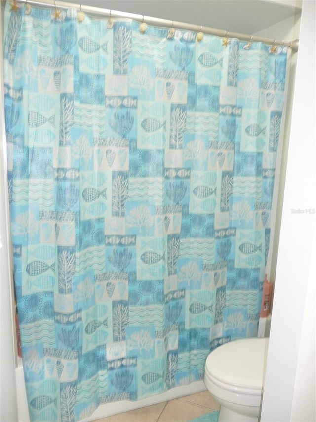 bathroom with toilet, tile patterned flooring, and shower / tub combo with curtain