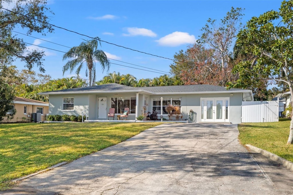 ranch-style house with central air condition unit, french doors, and a front lawn