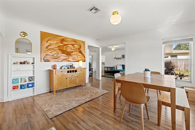 dining space with hardwood / wood-style floors and built in shelves