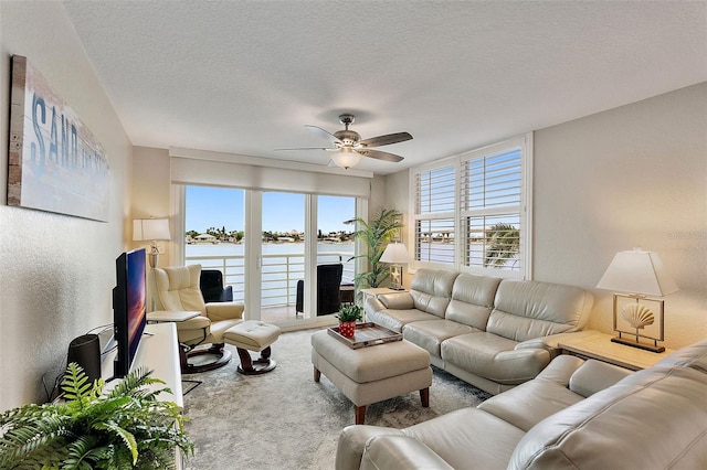 living room featuring ceiling fan, carpet flooring, and a textured ceiling