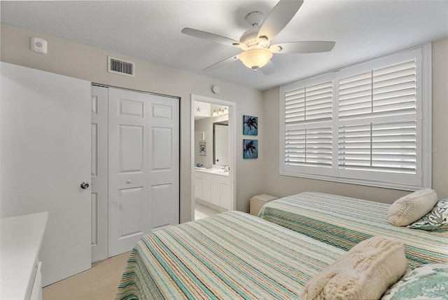 bedroom with connected bathroom, sink, ceiling fan, a closet, and light colored carpet