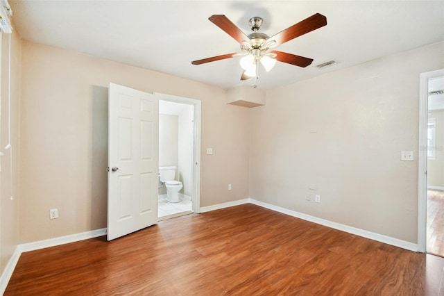 unfurnished bedroom with ceiling fan, ensuite bath, and wood-type flooring