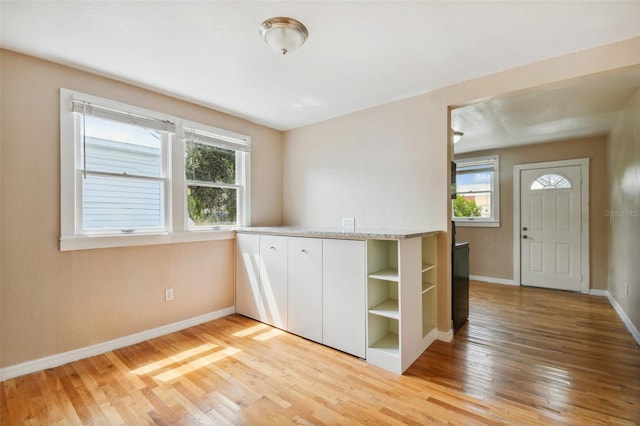 kitchen with white cabinets, a wealth of natural light, and light hardwood / wood-style flooring