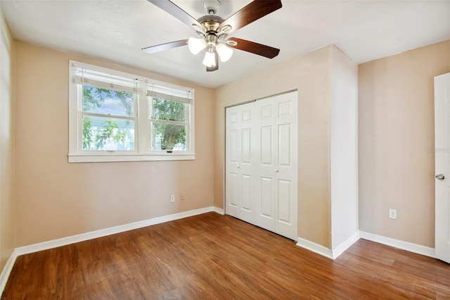 unfurnished bedroom with ceiling fan, a closet, and hardwood / wood-style flooring