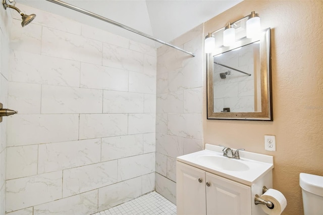 bathroom with a tile shower, vanity, and toilet