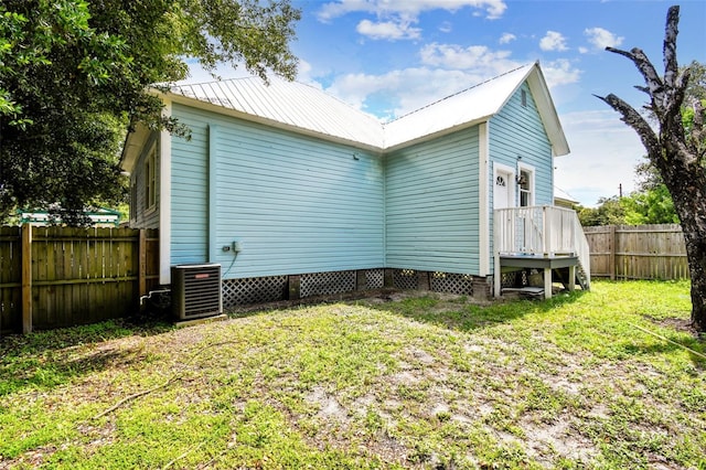 back of property with central AC unit and a yard