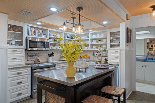 kitchen with backsplash, a tray ceiling, appliances with stainless steel finishes, white cabinets, and wooden ceiling