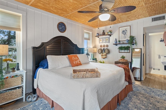 bedroom with ensuite bathroom, wood ceiling, wooden walls, ceiling fan, and wood-type flooring