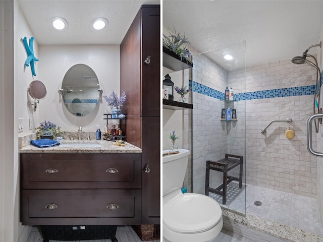 bathroom with toilet, vanity, a shower with door, and a textured ceiling