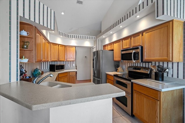 kitchen featuring light tile patterned floors, kitchen peninsula, sink, and stainless steel appliances