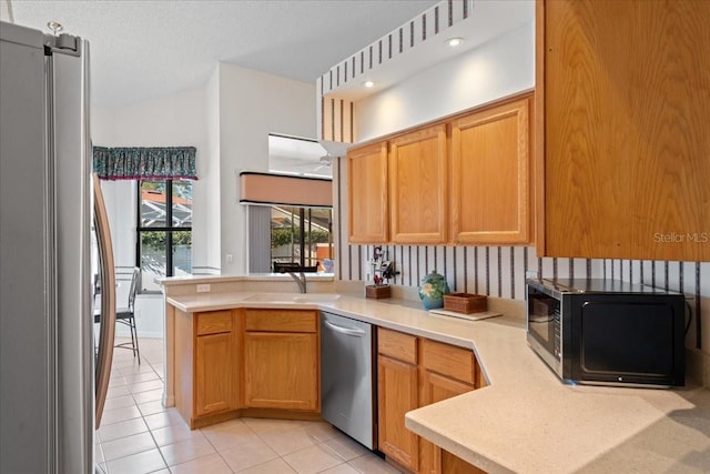 kitchen featuring sink, kitchen peninsula, light tile patterned floors, and stainless steel appliances