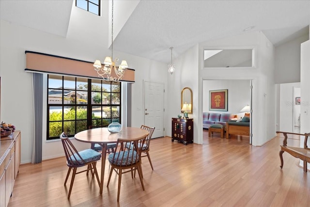 dining room featuring high vaulted ceiling, a chandelier, and light hardwood / wood-style flooring