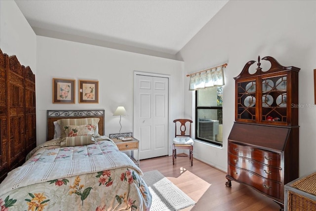 bedroom with cooling unit, a closet, lofted ceiling, and light hardwood / wood-style floors