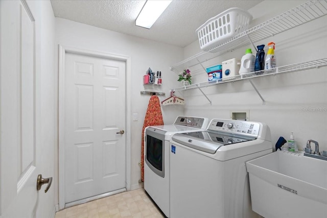 laundry area featuring sink, washing machine and clothes dryer, and a textured ceiling