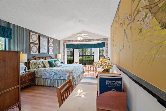 bedroom featuring ceiling fan, vaulted ceiling, a textured ceiling, and hardwood / wood-style floors