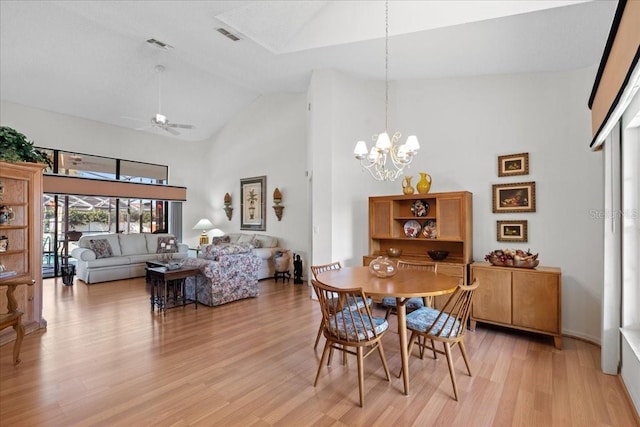 dining room featuring ceiling fan with notable chandelier, light hardwood / wood-style flooring, and high vaulted ceiling