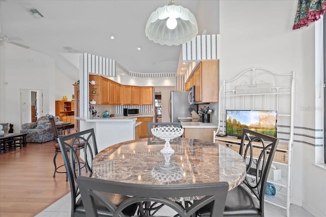 tiled dining area with ceiling fan, a high ceiling, and a healthy amount of sunlight