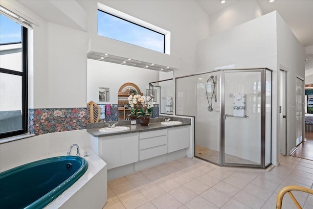 bathroom featuring a high ceiling, tile patterned flooring, separate shower and tub, and vanity