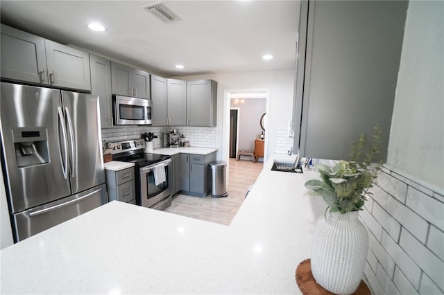 kitchen featuring sink, gray cabinets, tasteful backsplash, and appliances with stainless steel finishes