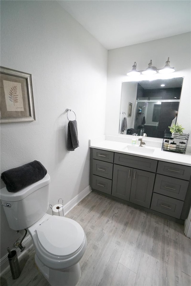 bathroom featuring walk in shower, hardwood / wood-style floors, vanity, and toilet