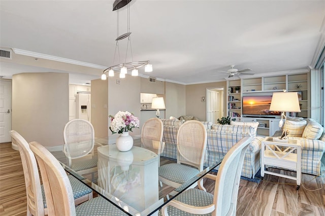 dining room with hardwood / wood-style flooring, built in shelves, and crown molding